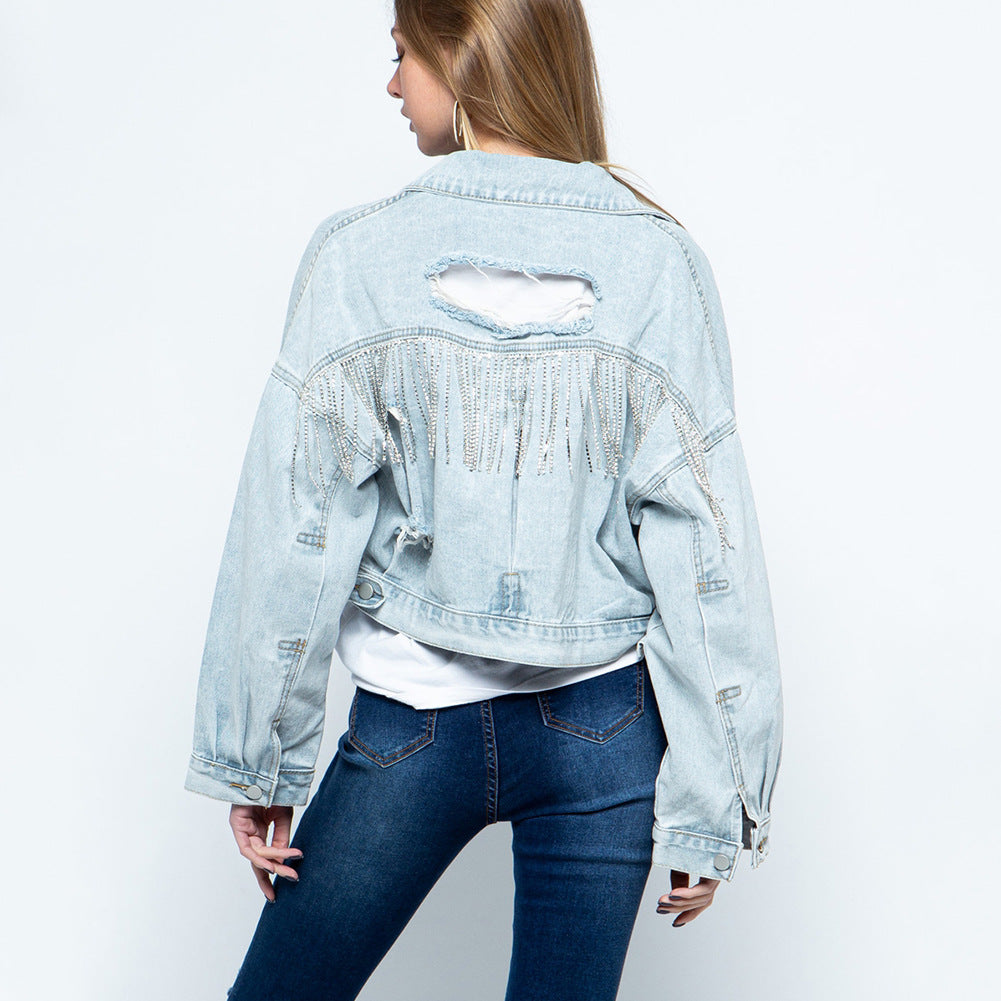 Stylish denim jacket for women with ripped details, rhinestone embellishments, tassel accents, and long sleeves.