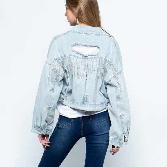Stylish denim jacket for women with ripped details, rhinestone embellishments, tassel accents, and long sleeves.